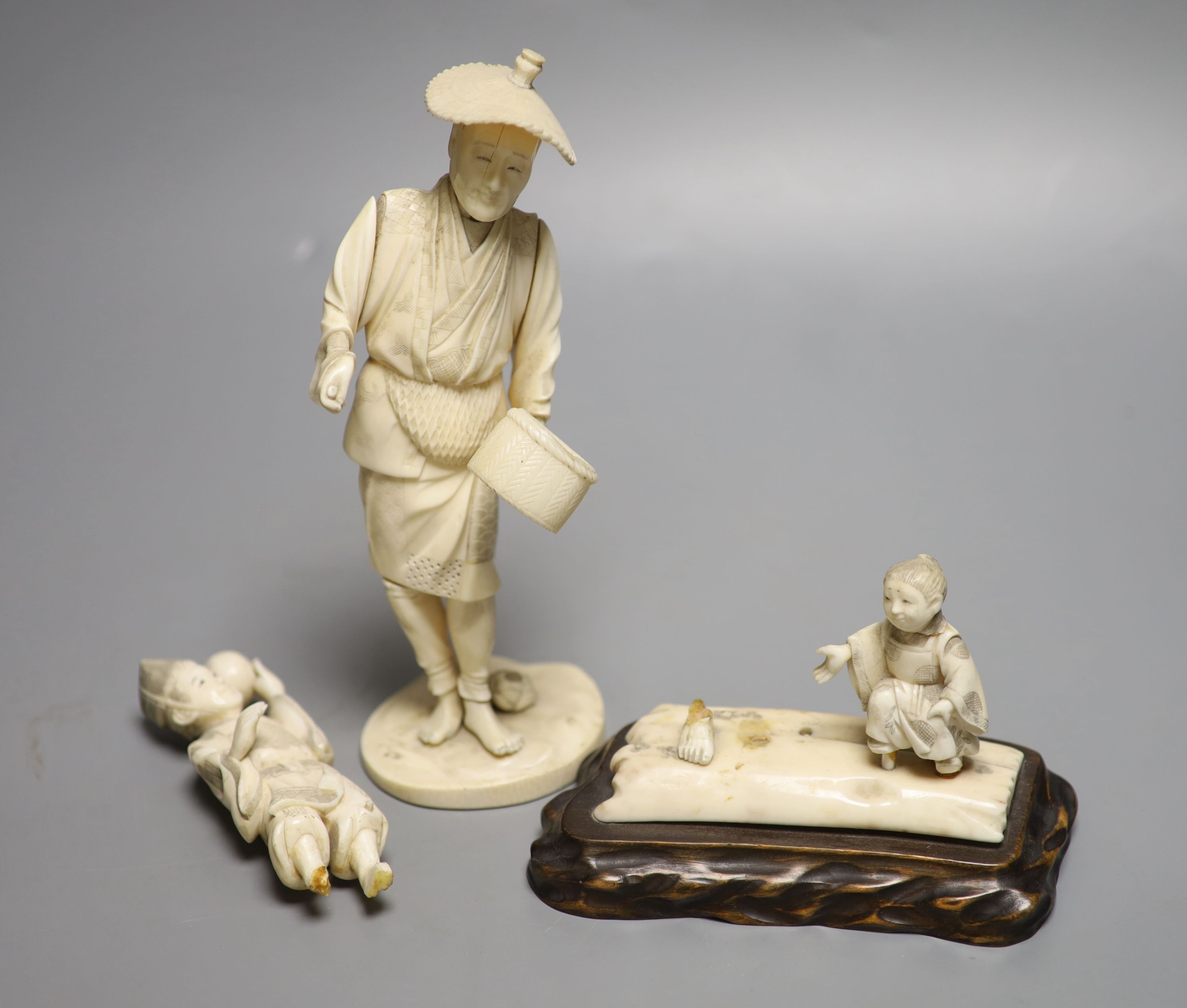 A Japanese Meiji period sectional carved ivory of a man, height 23cm and a Meiji ivory group (damaged)